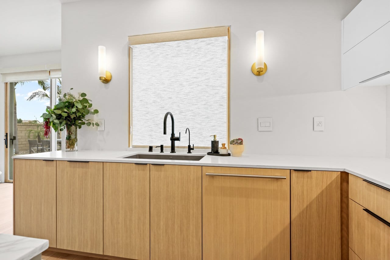 Modern kitchen with white oak cabinetry, quartz counters and black gooseneck faucet