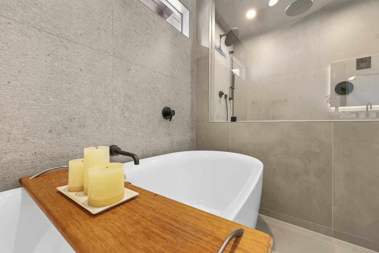 Modern bathroom with freestanding tub and glass-enclosed shower in gray tile