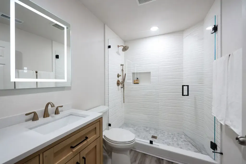 Modern bathroom with glass shower, white subway tile and warm wood vanity