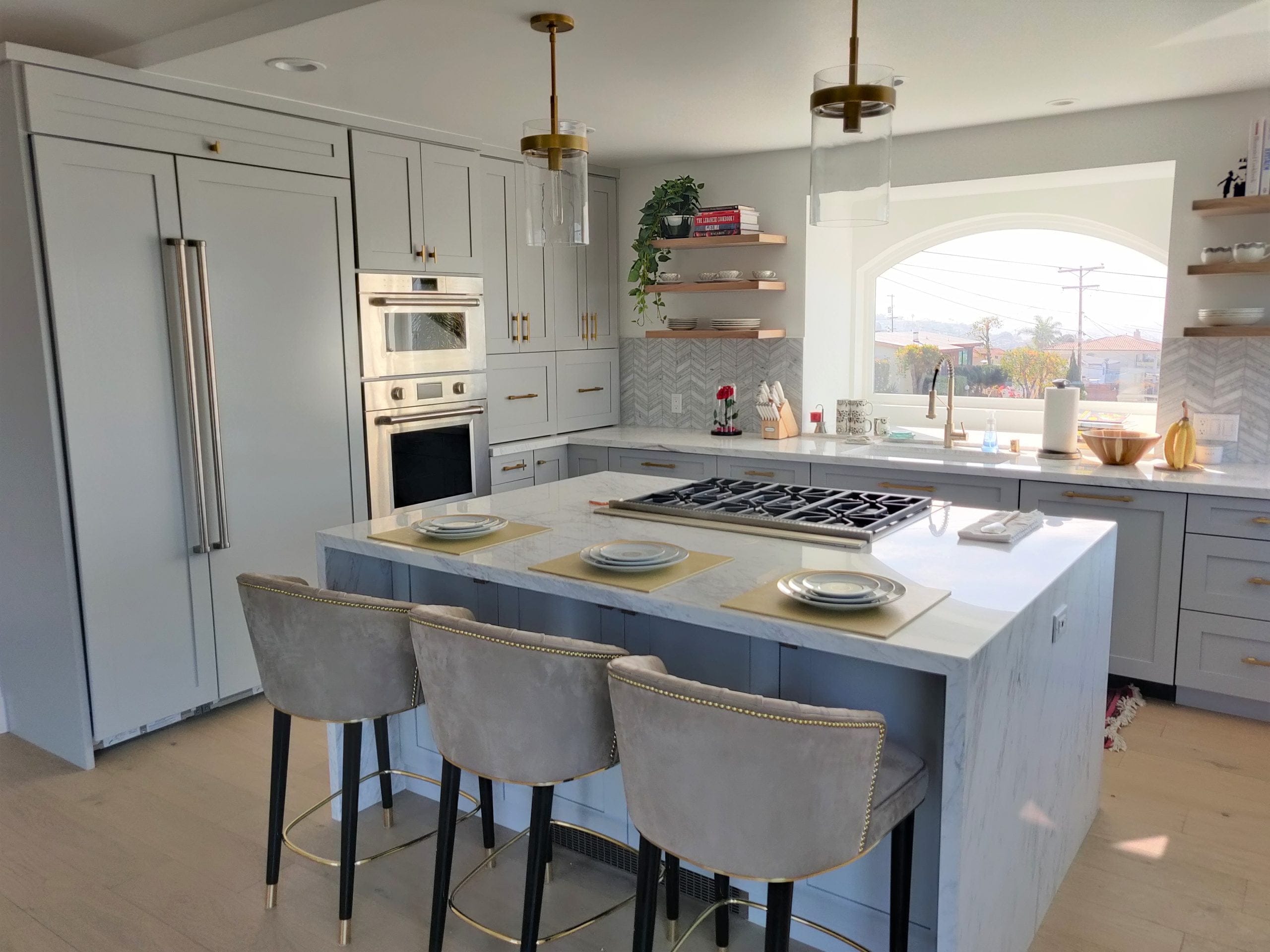 modern gray kitchen with marble island, gas cooktop, and brass pendant lighting