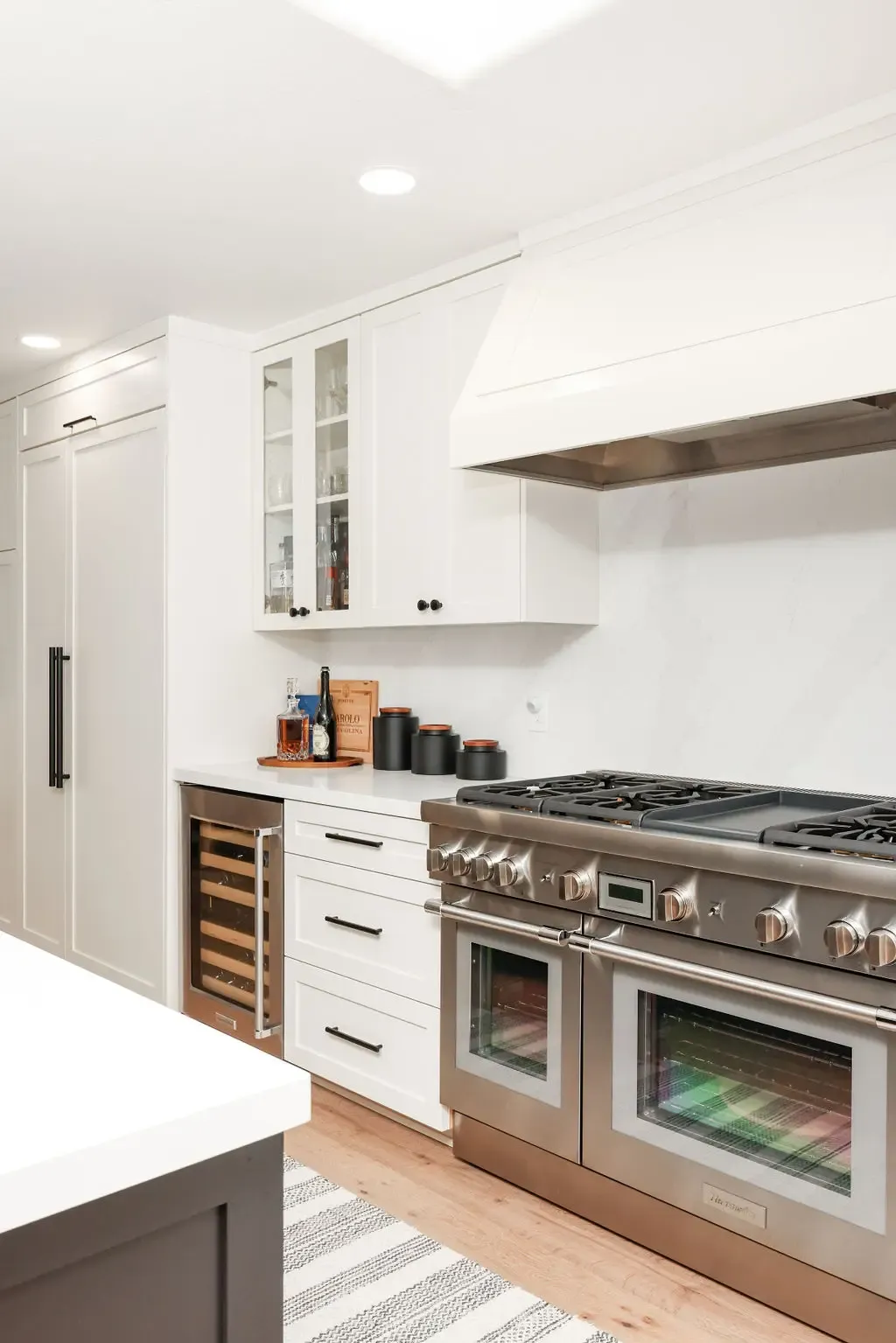 Modern kitchen with double stainless range, custom hood and wine fridge