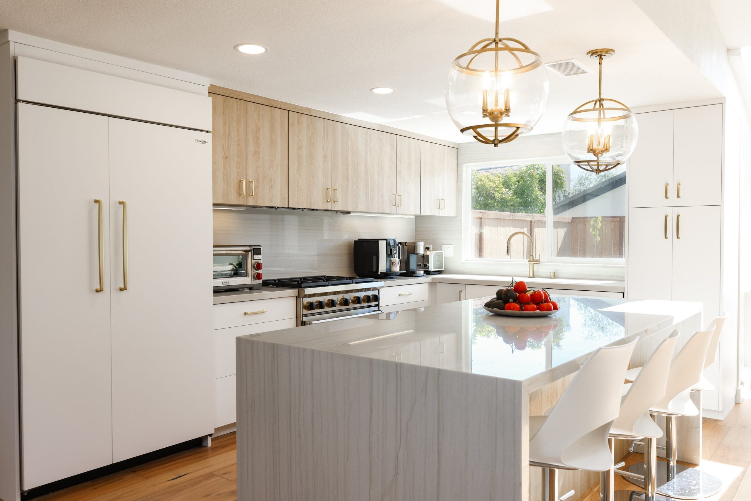 Modern kitchen with paneled fridge, oak uppers and marble waterfall island bar