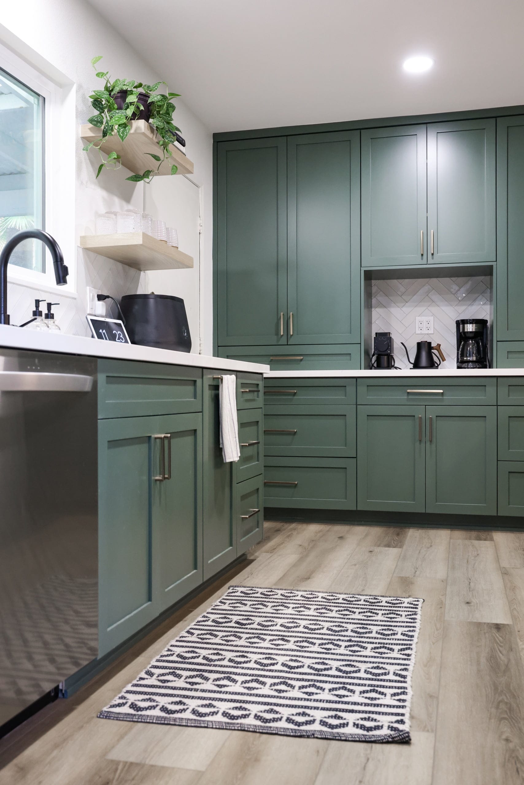 Modern kitchen with sage green shaker cabinets, quartz counters and light wood flooring