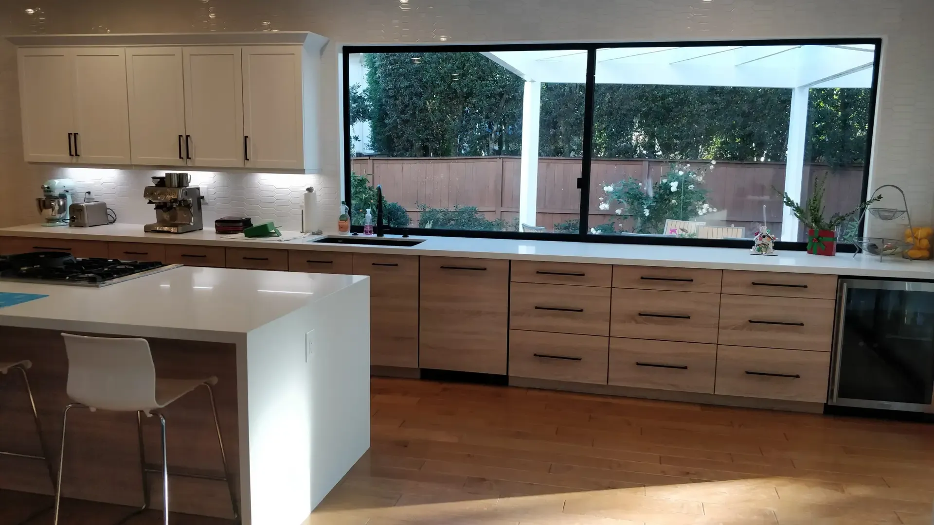 Modern kitchen with white quartz island, wood-grain cabinetry and large picture window