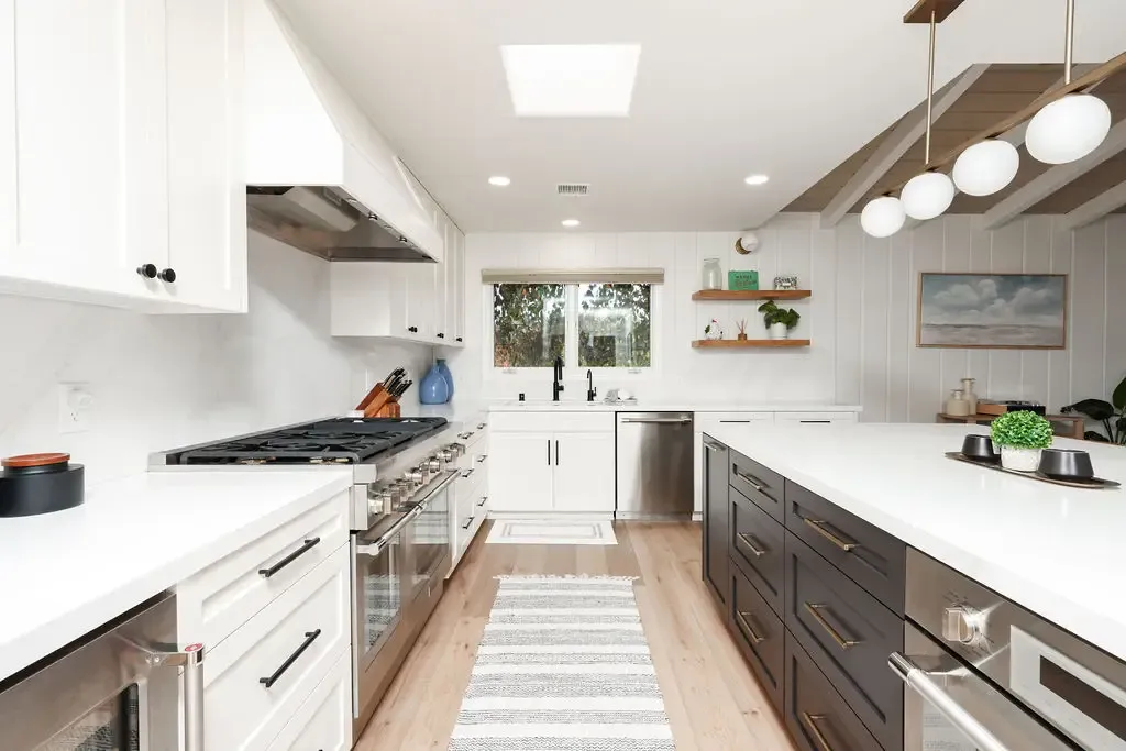 Modern kitchen with white uppers, dark lower cabinets and waterfall quartz island
