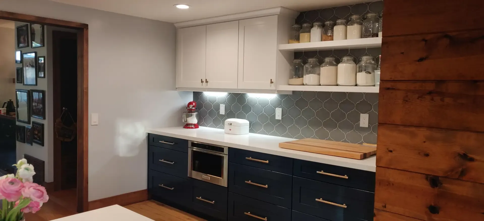 Navy and white kitchen with open shelving, brass pulls and patterned tile backsplash