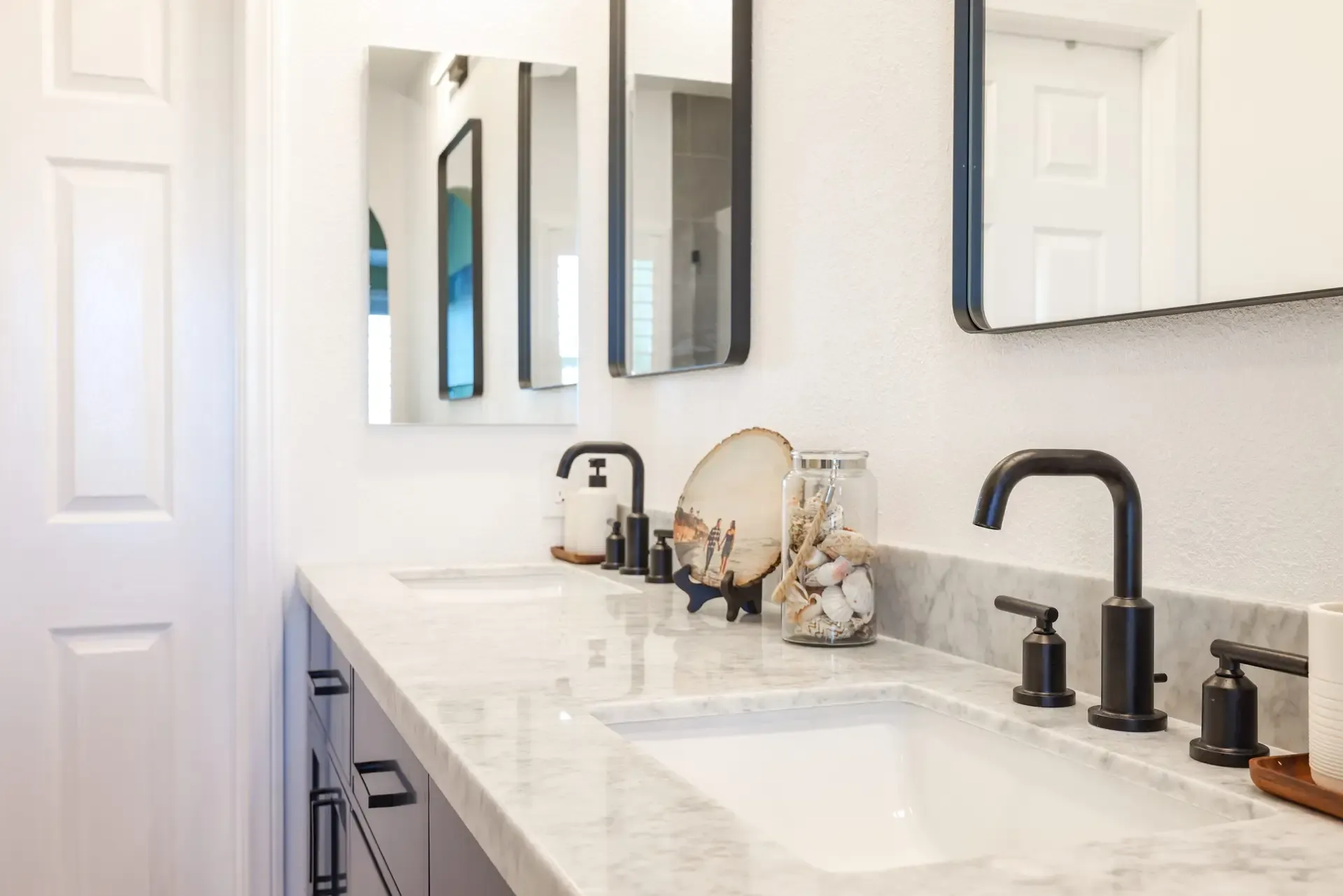 Navy double vanity with marble countertop and matte-black widespread faucets