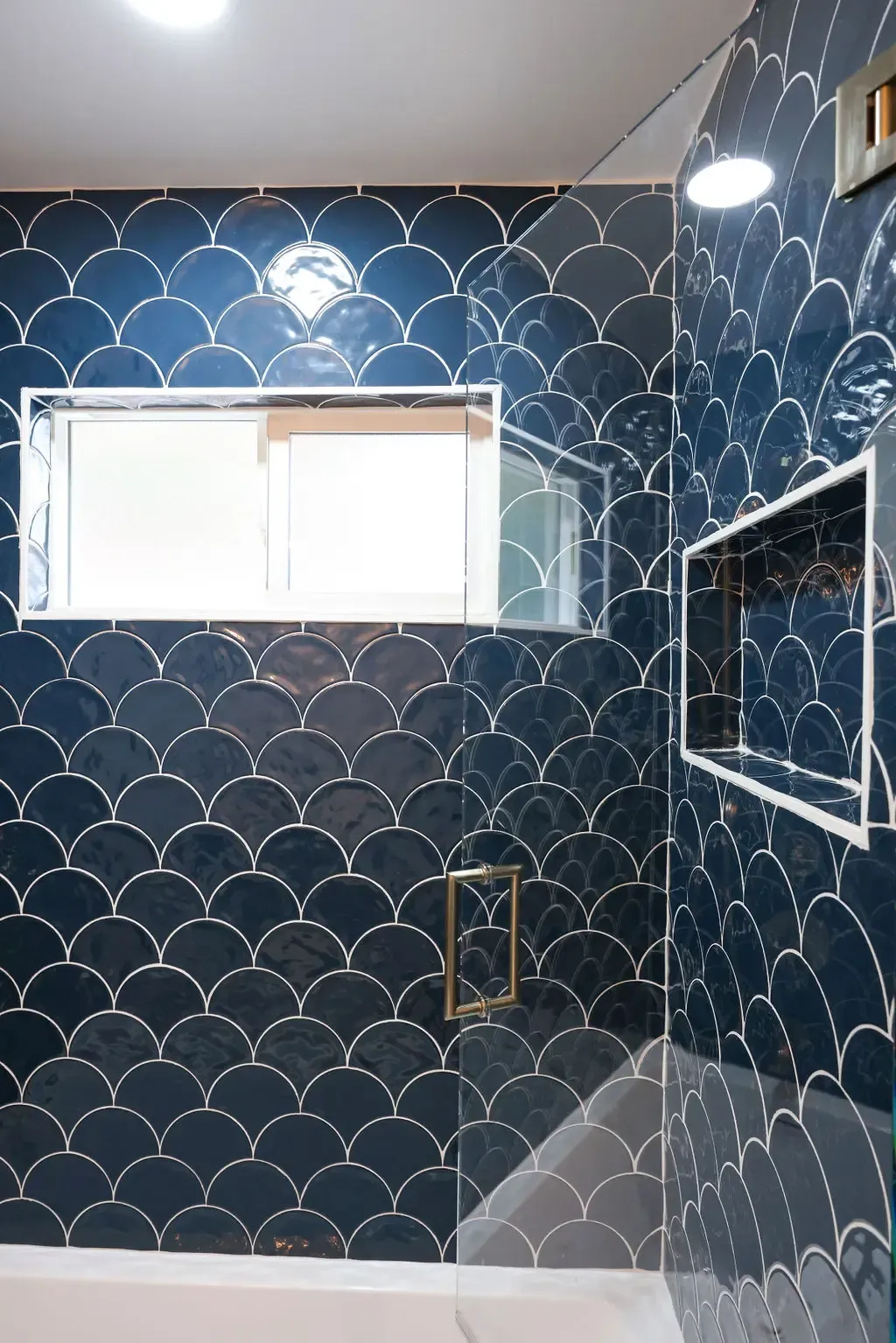 Navy fishscale tile shower with recessed niche and frosted glass-block window