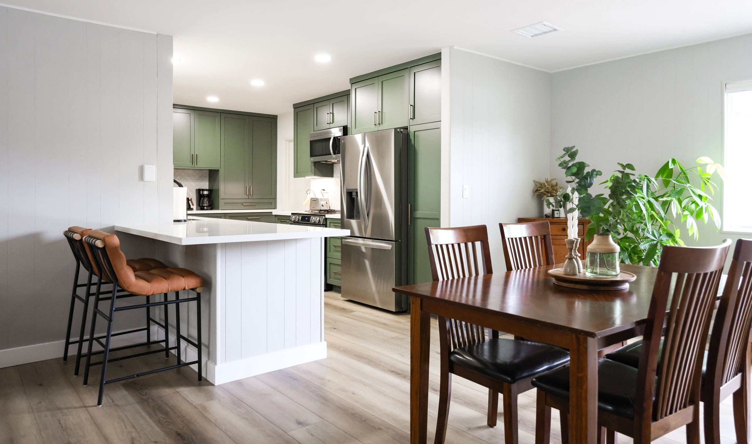 Open-concept kitchen and dining area with green cabinetry and wood farmhouse table