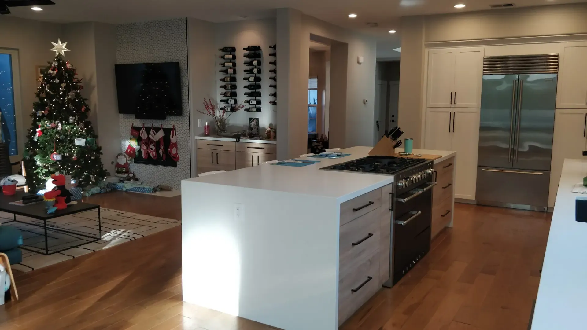 Open-concept kitchen and living area with white island and wall-mounted wine racks
