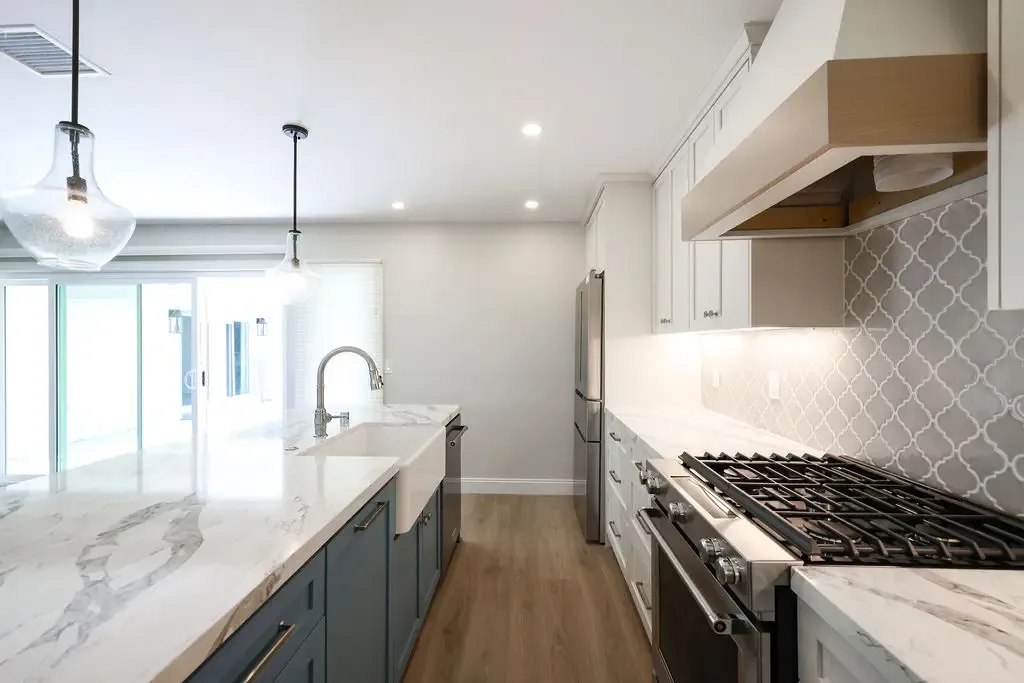 Open-concept kitchen with marble island, blue lower cabinets, and stainless gas cooktop