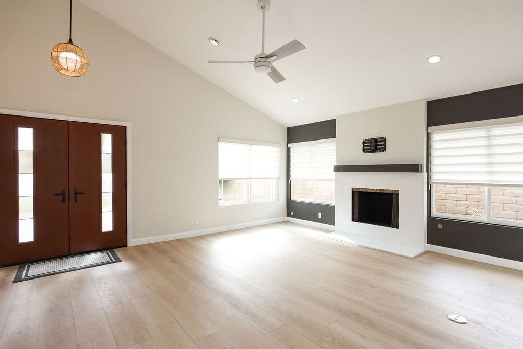Open great room with vaulted ceiling, double wood entry doors and modern fireplace