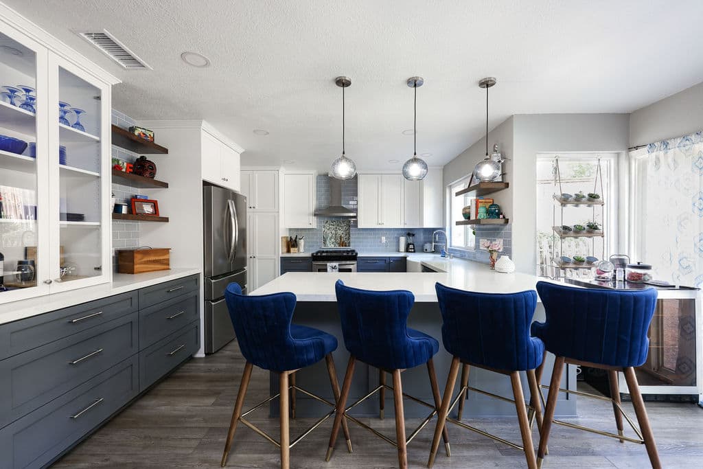 Open kitchen with gray island, blue velvet barstools and floating wood shelves