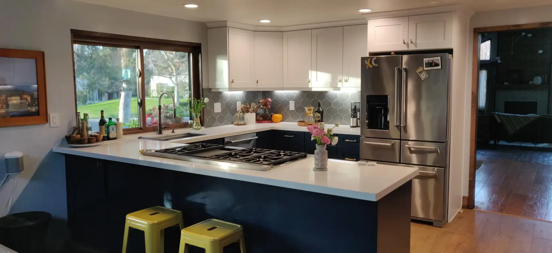 Open kitchen with navy island, white quartz counters and stainless appliances