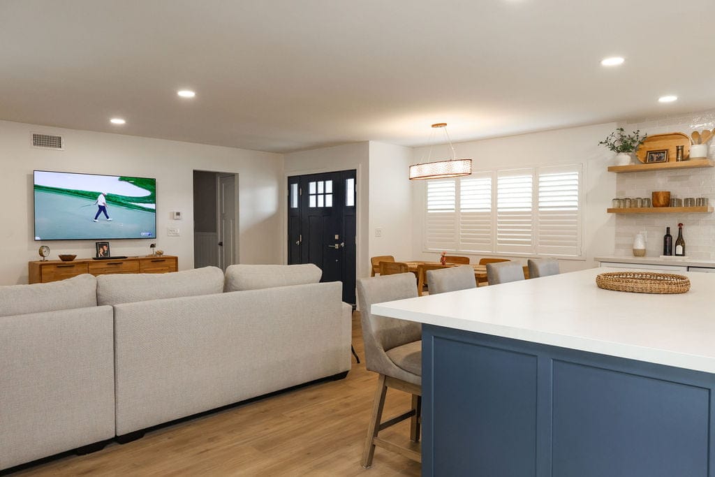 Open living and dining area with blue kitchen island and wood floors