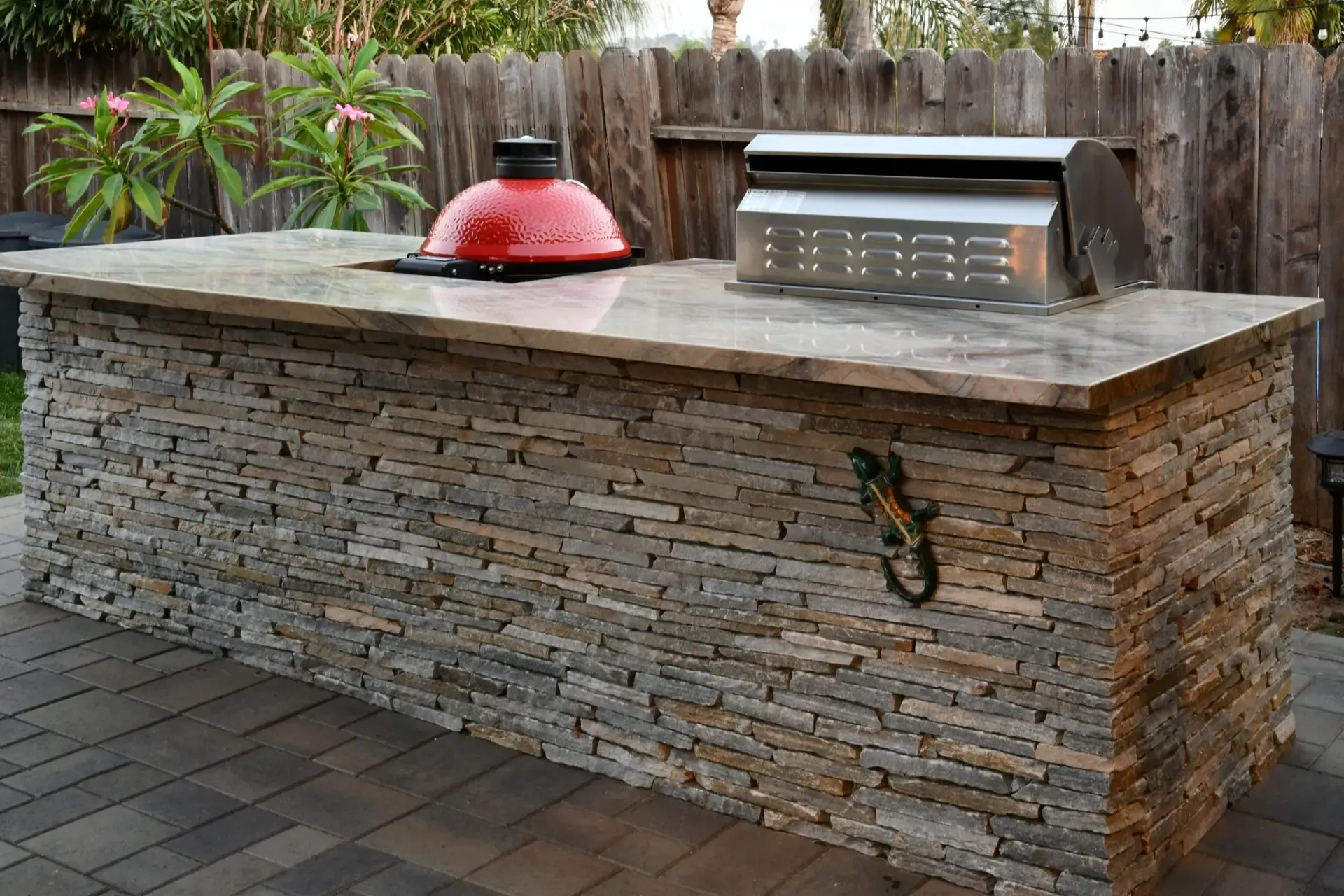 Outdoor kitchen with stacked stone base, stone countertop and kamado grill