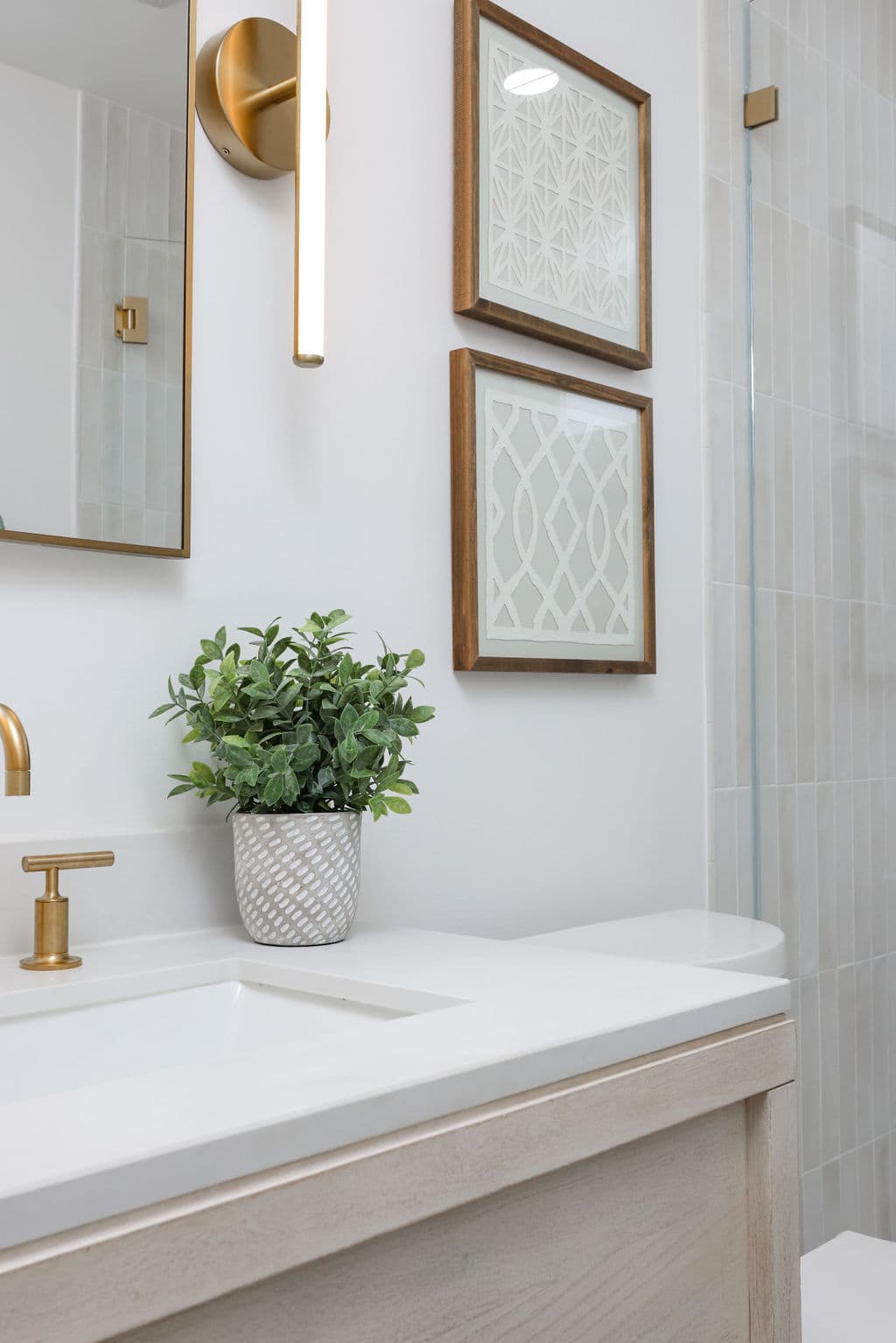 powder room vignette with brushed gold faucet, framed art and white oak vanity