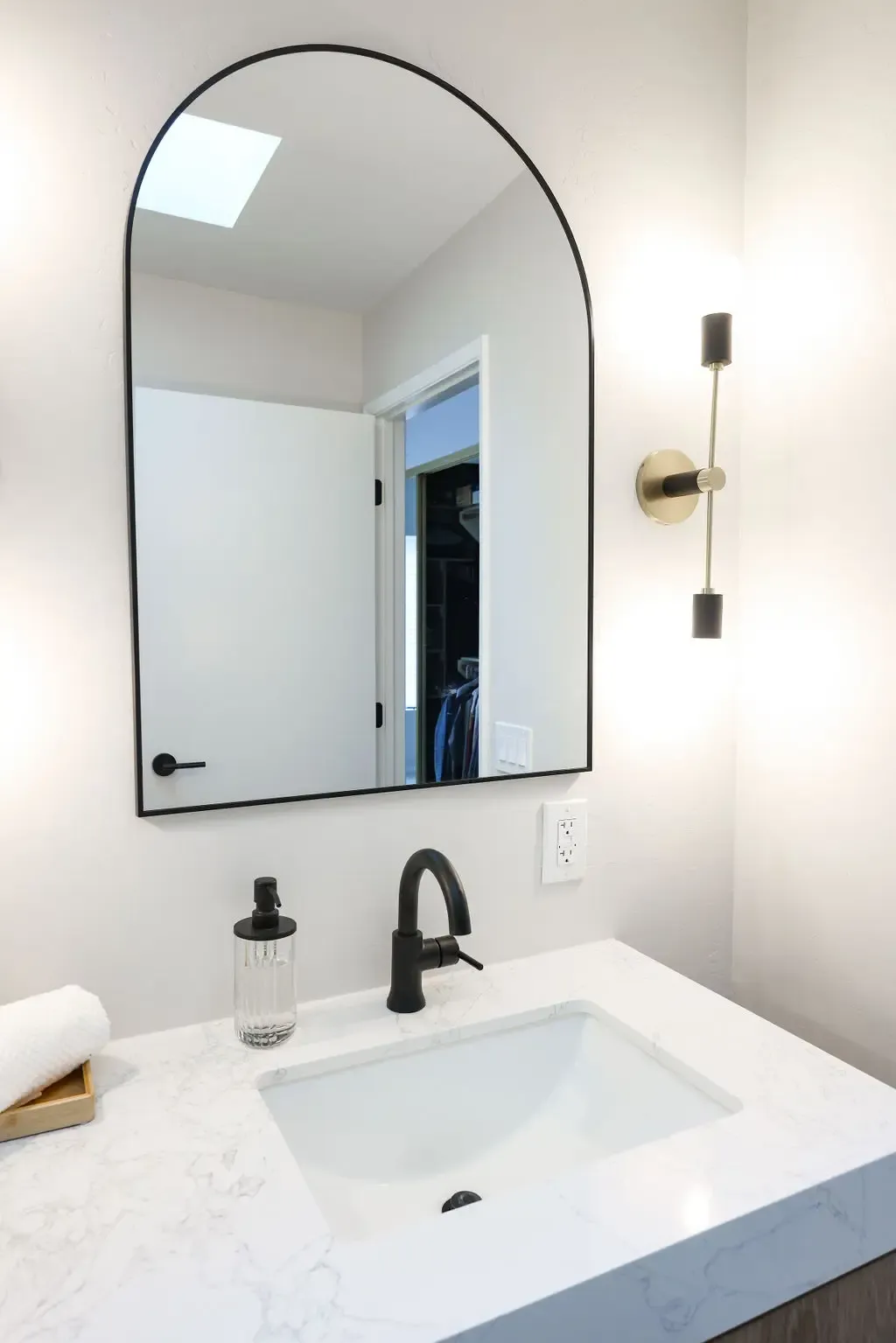 Powder vanity with marble countertop, arched mirror and matte black faucet