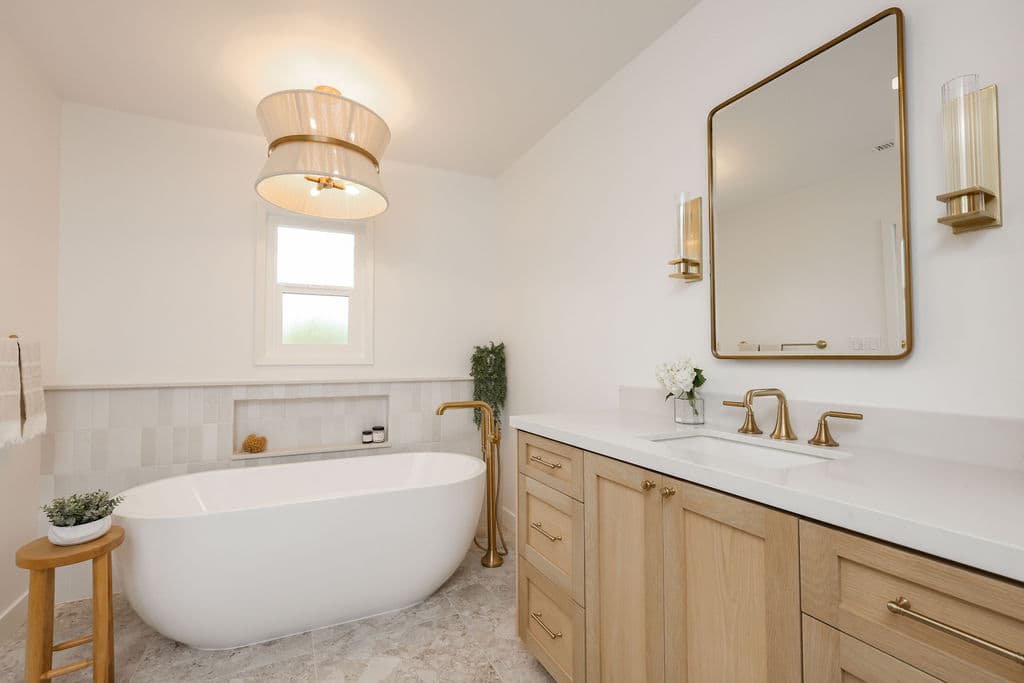 primary bath with freestanding tub, brass floor filler and white oak vanity