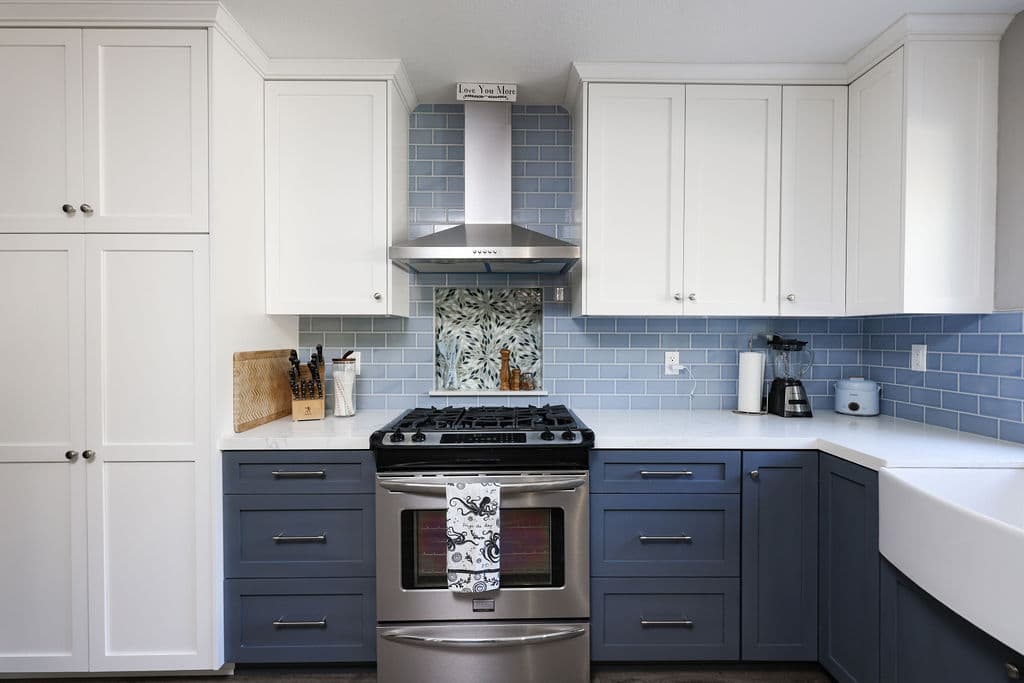 Range wall with stainless hood, mosaic accent tile and navy shaker drawers