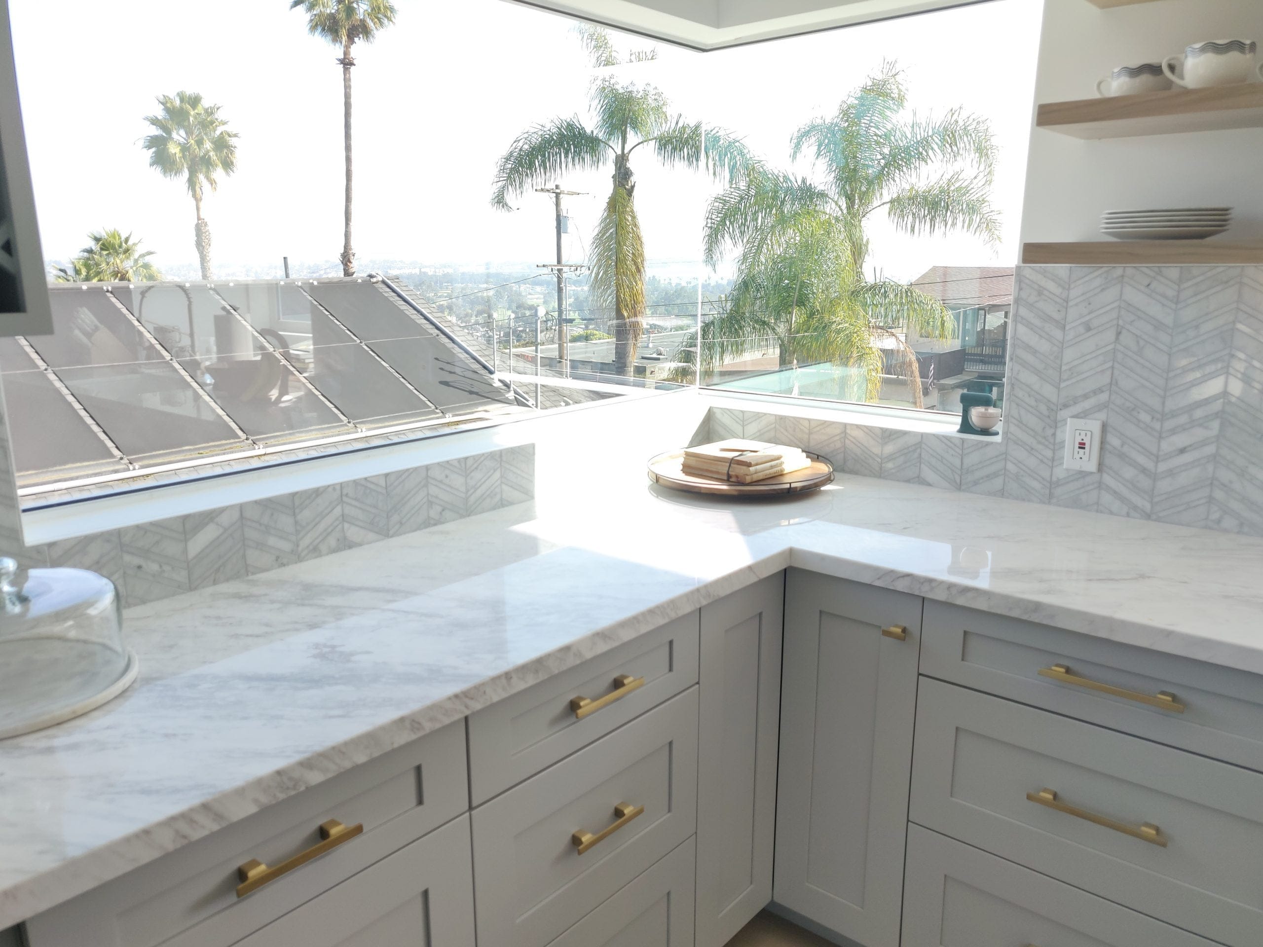 Remodeled kitchen corner with white marble counters, gray shaker cabinets and brass pulls