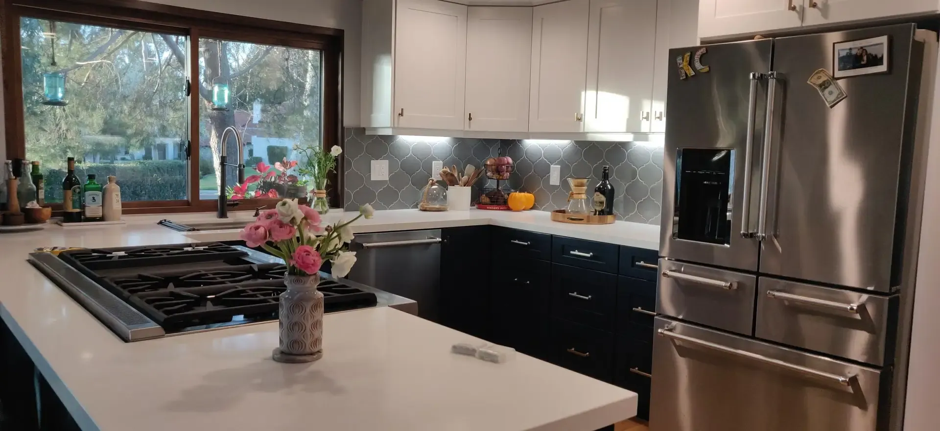 Remodeled kitchen featuring gas cooktop island, quartz counters and arabesque tile backsplash