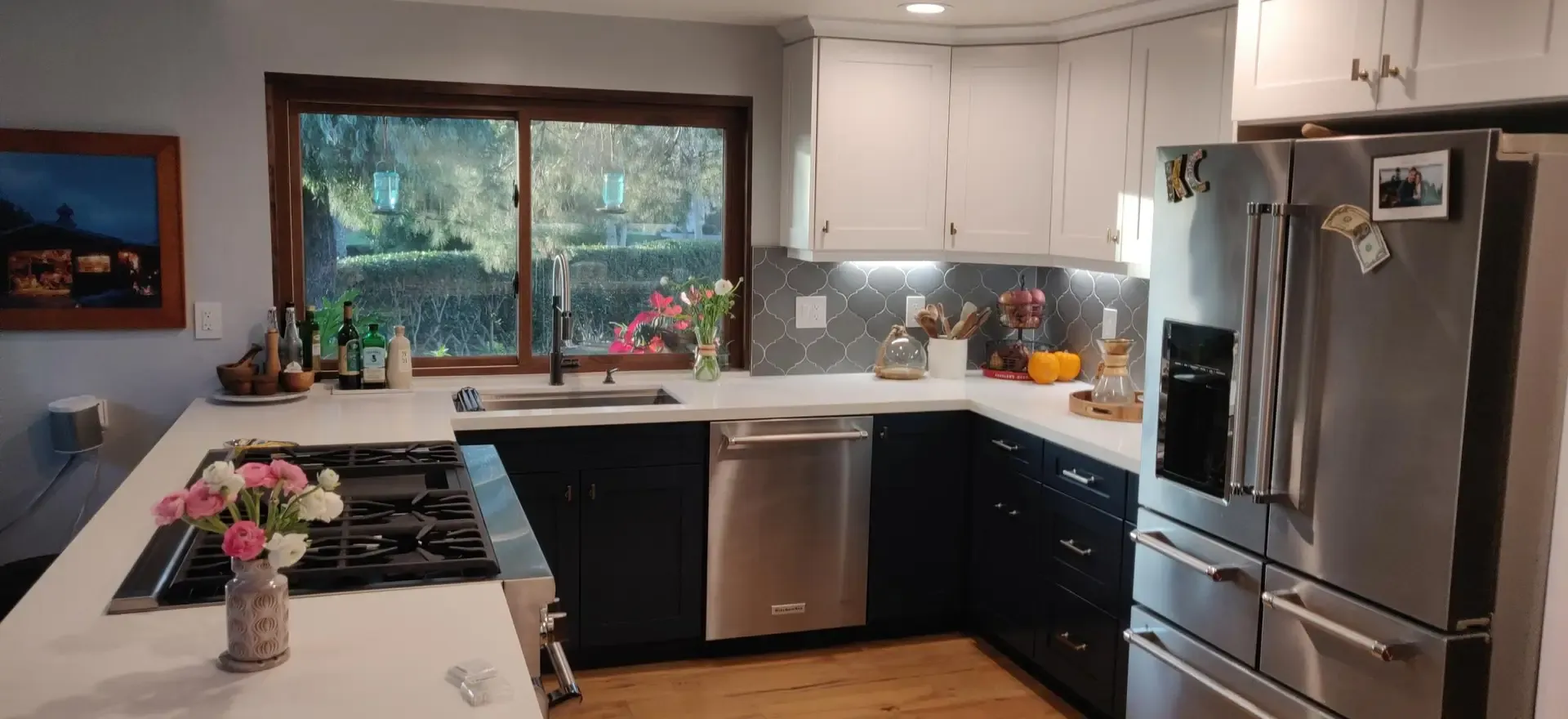remodeled kitchen with navy lower cabinets, white quartz counters, gas cooktop and stainless appliances
