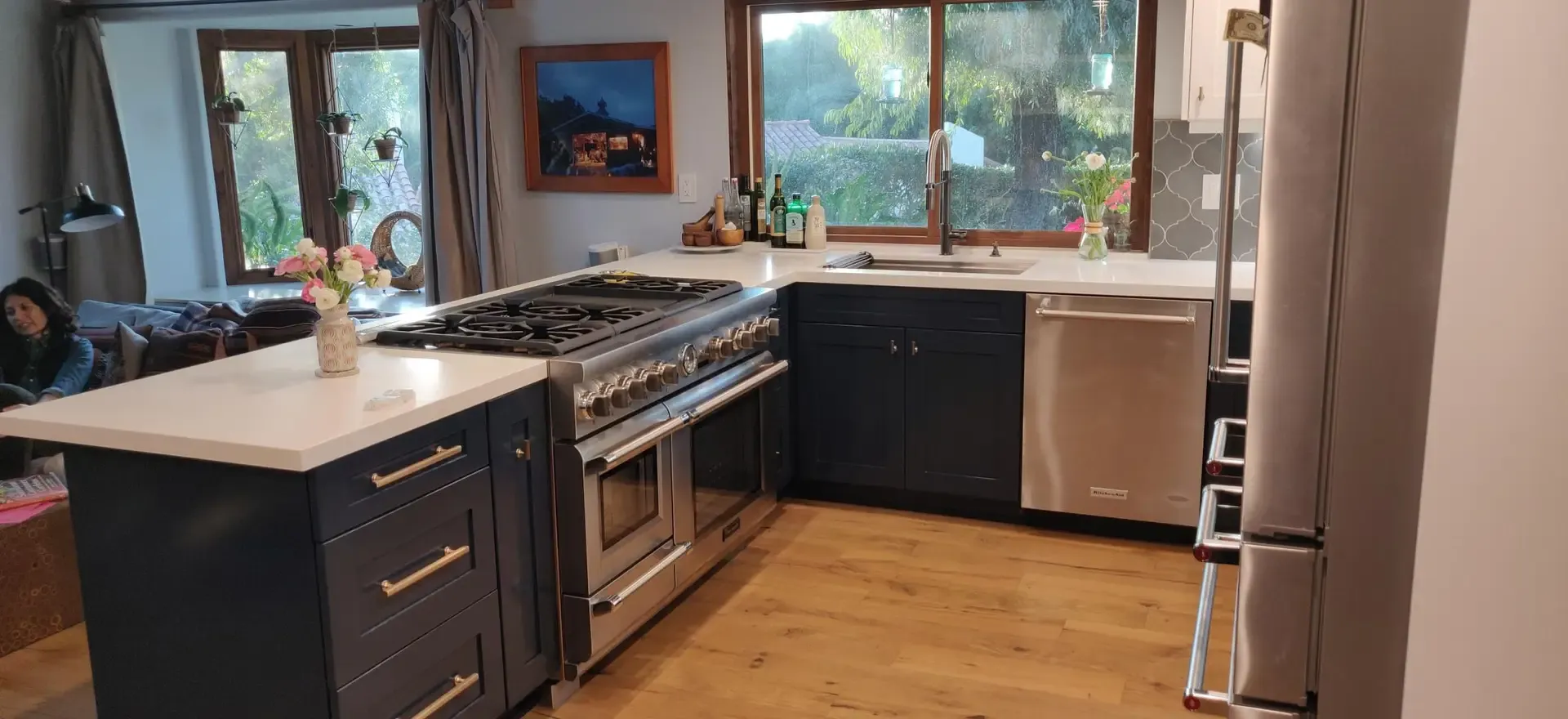 Renovated kitchen with navy cabinetry, pro range and oak flooring near windows