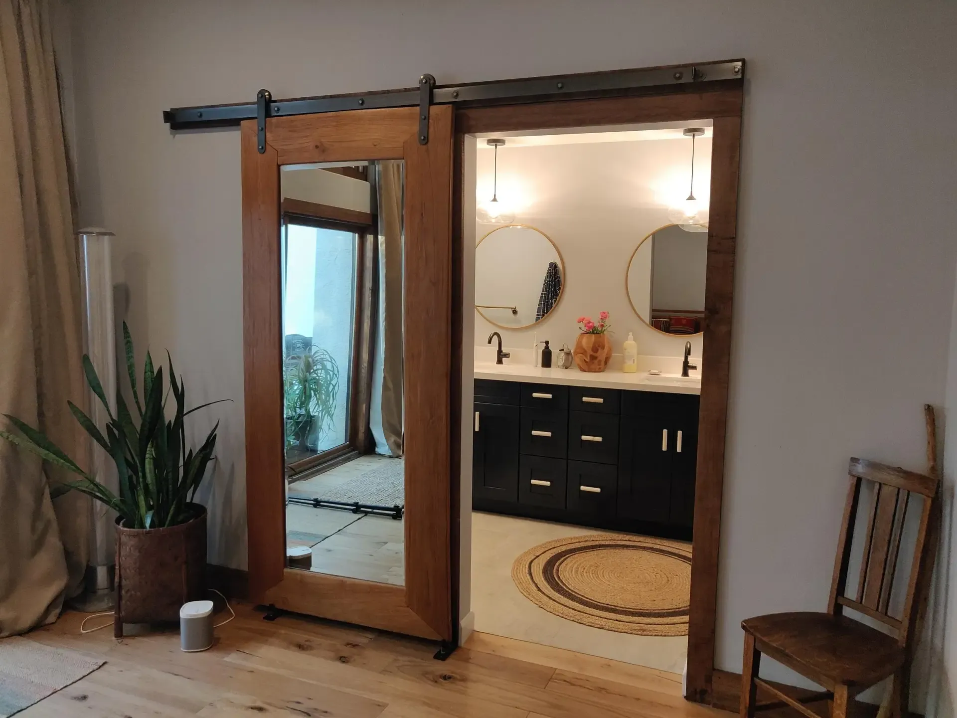 Rustic sliding barn door framing a dark vanity and round soaking tub beyond