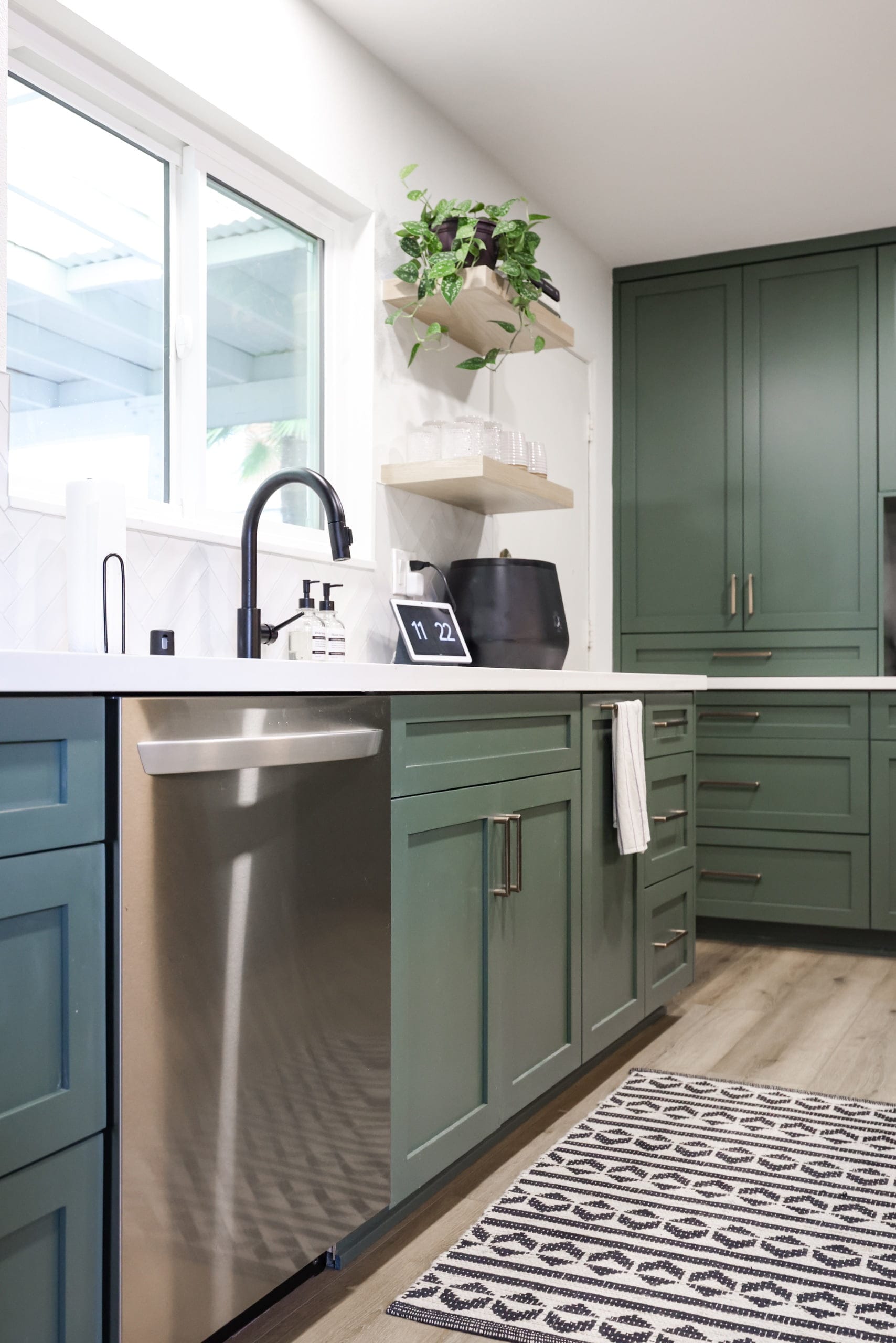 Sage green kitchen base cabinets with stainless dishwasher and black gooseneck faucet