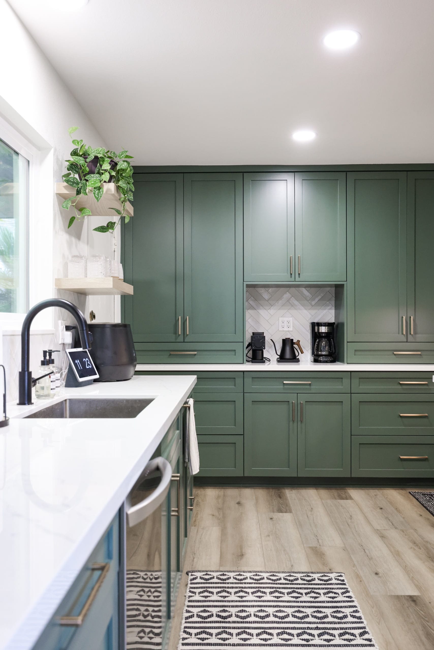 Sage green shaker cabinets with white quartz counters, brass pulls and herringbone backsplash