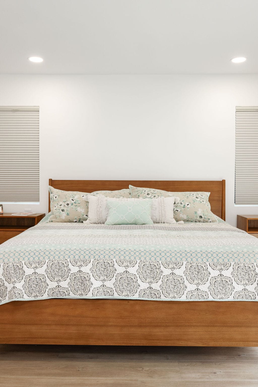 Serene bedroom with walnut bed frame, floral bedding and flanking nightstands
