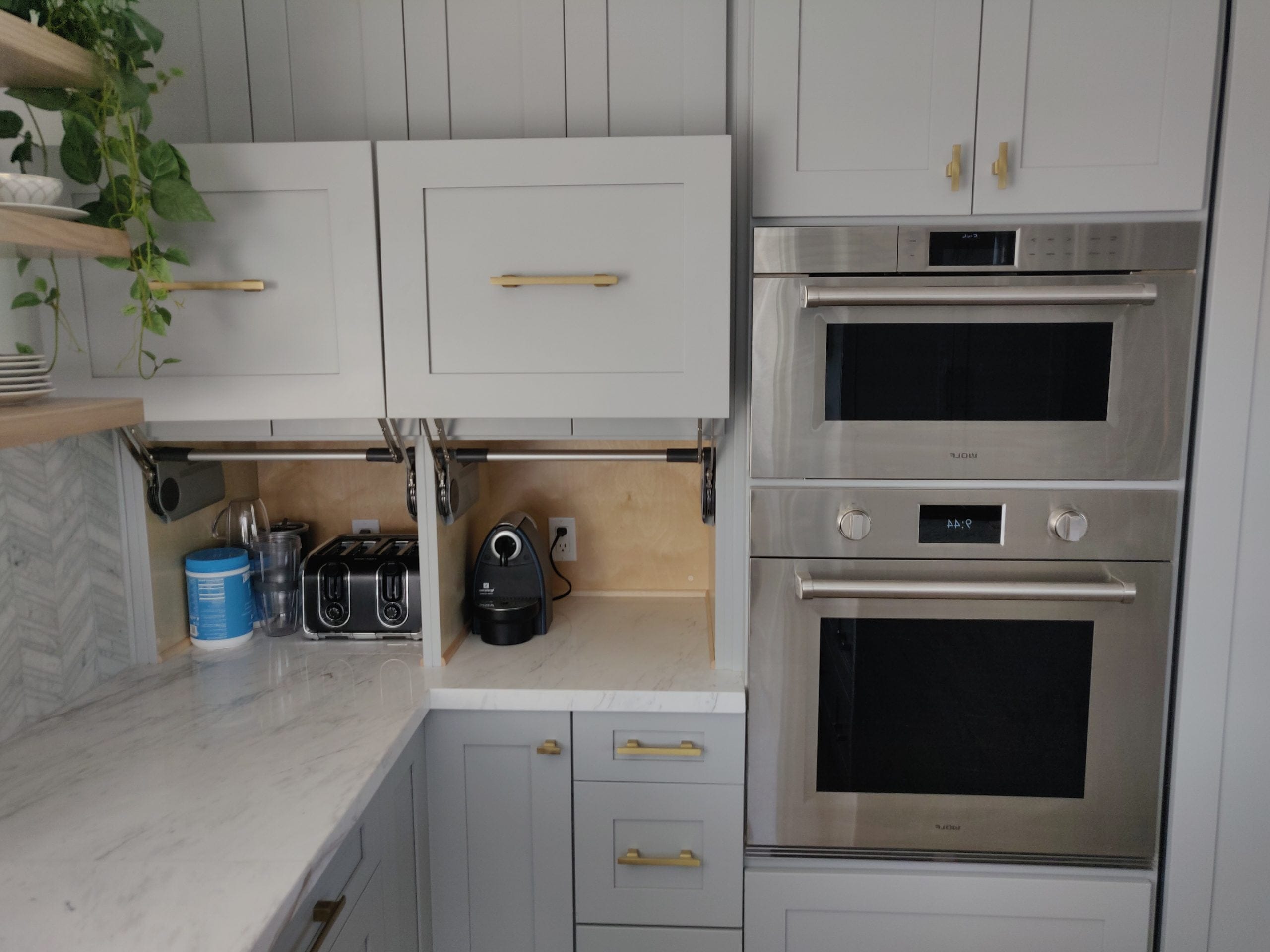 shaker cabinetry with hidden appliance garages flanking stainless double wall ovens
