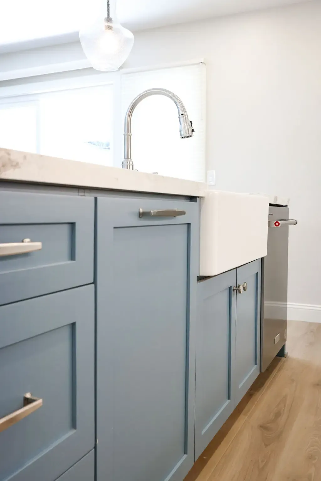 Slate-blue shaker cabinetry with apron-front sink and quartz countertop