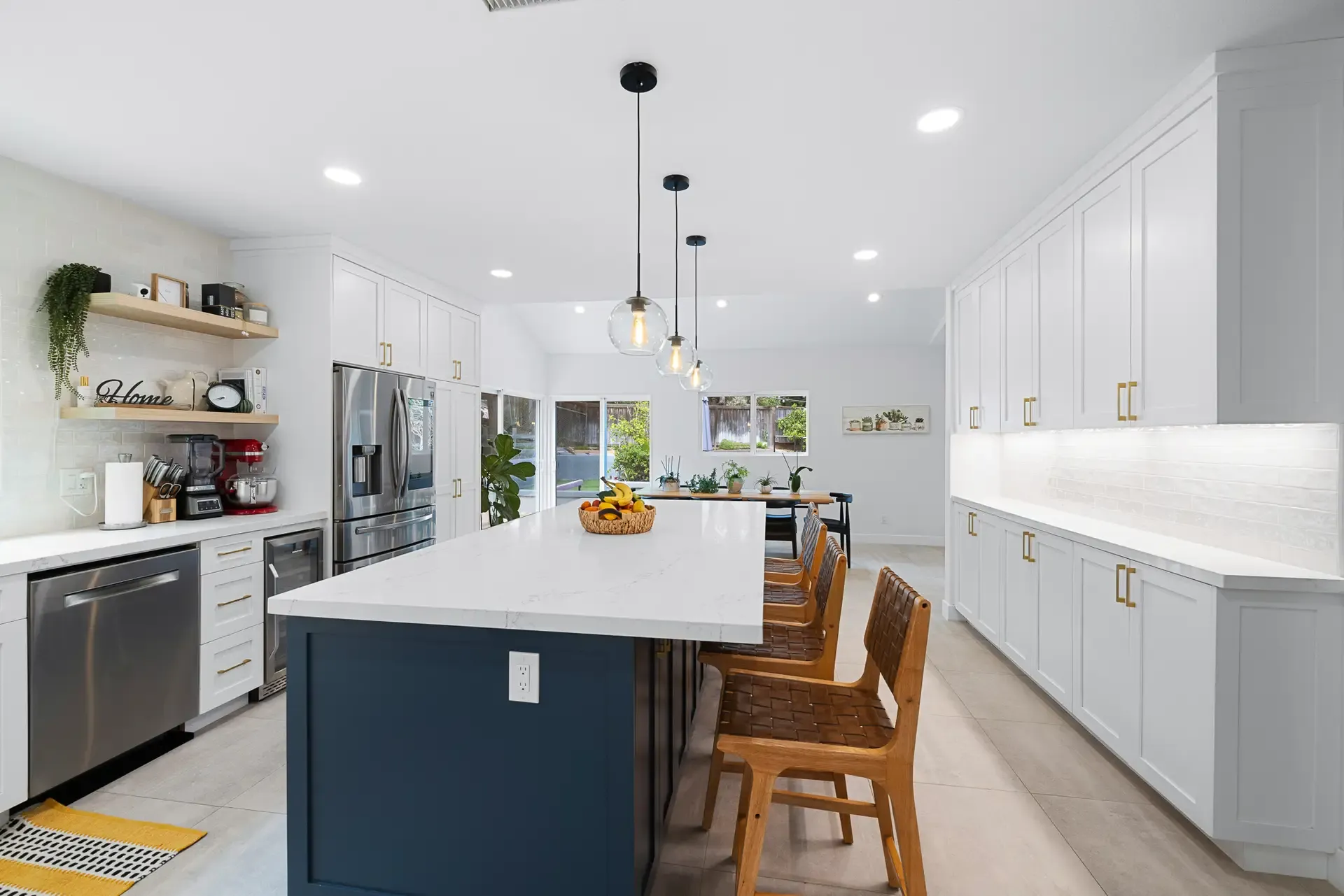 Spacious kitchen with navy island, quartz top and white perimeter cabinetry