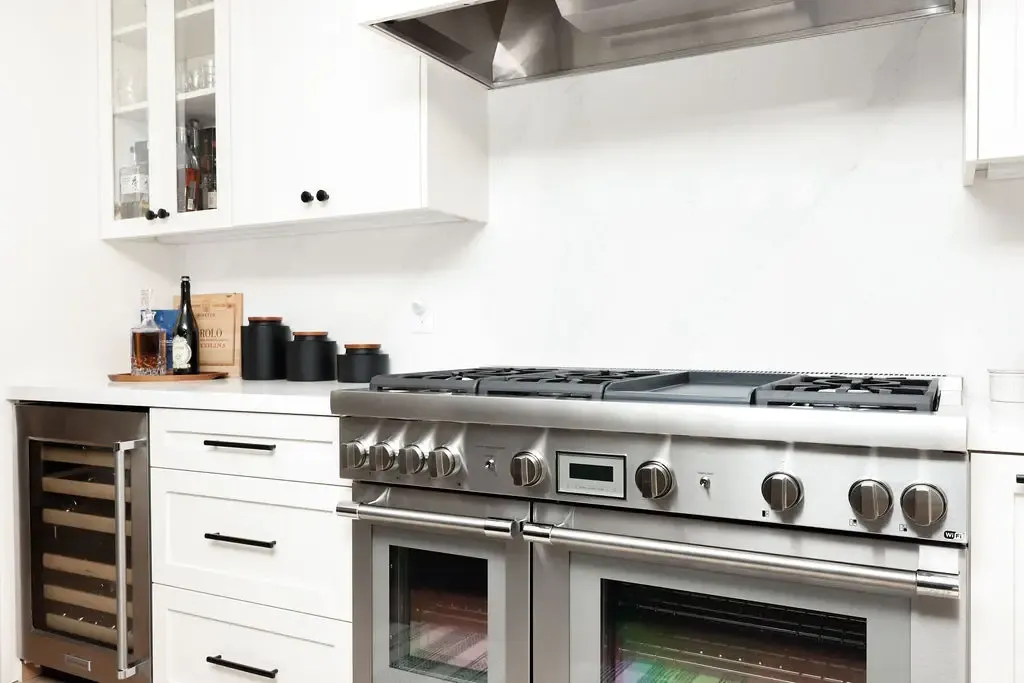Stainless professional six-burner range against white marble-look backsplash