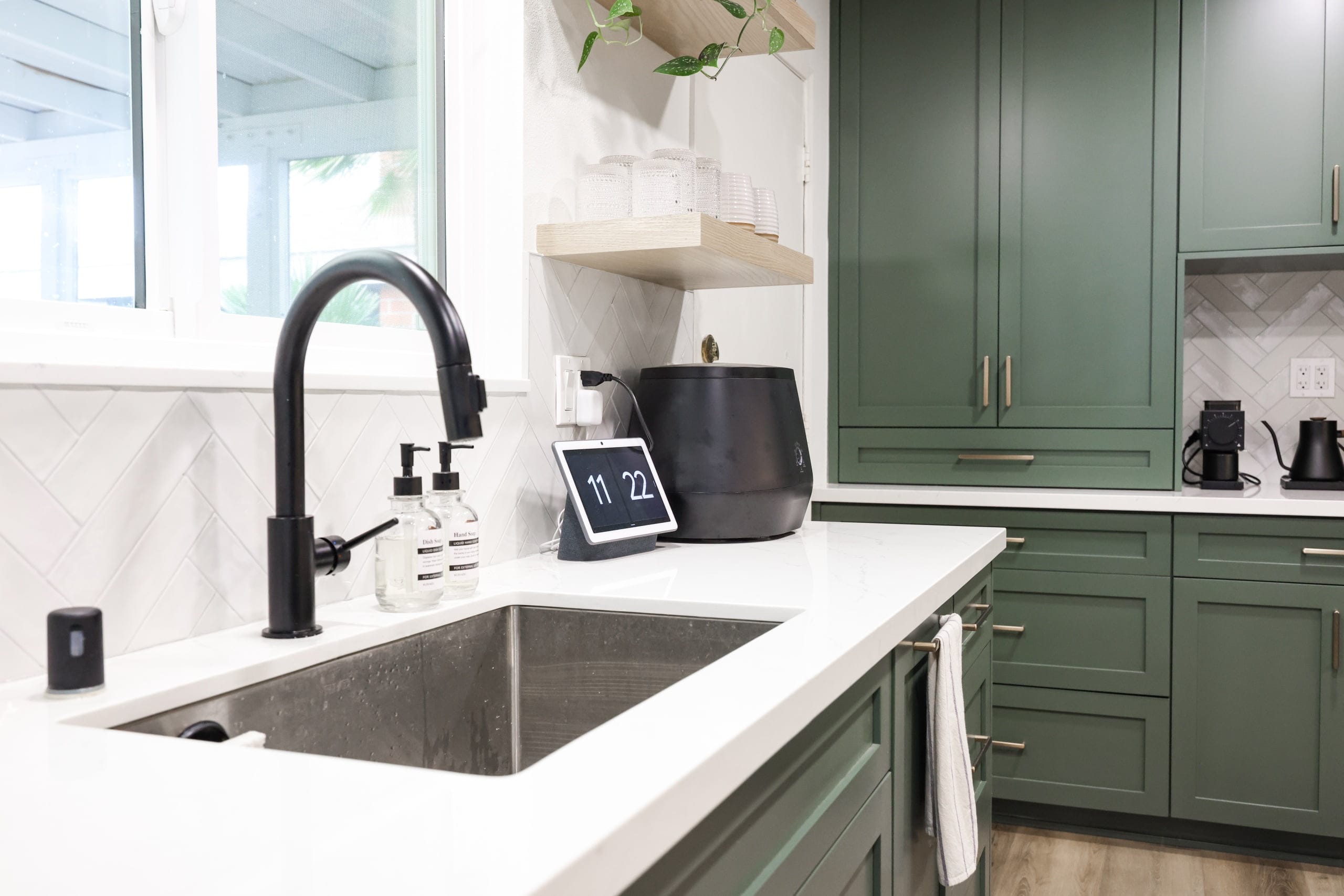 Stainless undermount sink with black faucet, white quartz counter and green shaker cabinets