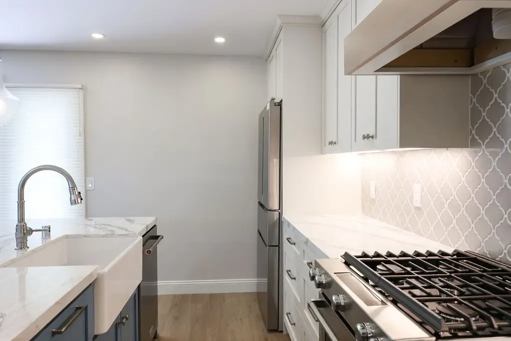 Transitional kitchen with farmhouse sink, stainless refrigerator, and patterned tile wall