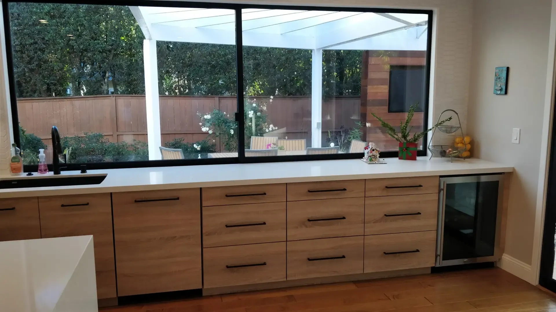 Two-tone kitchen run with wood drawers, white counters and built-in wine fridge