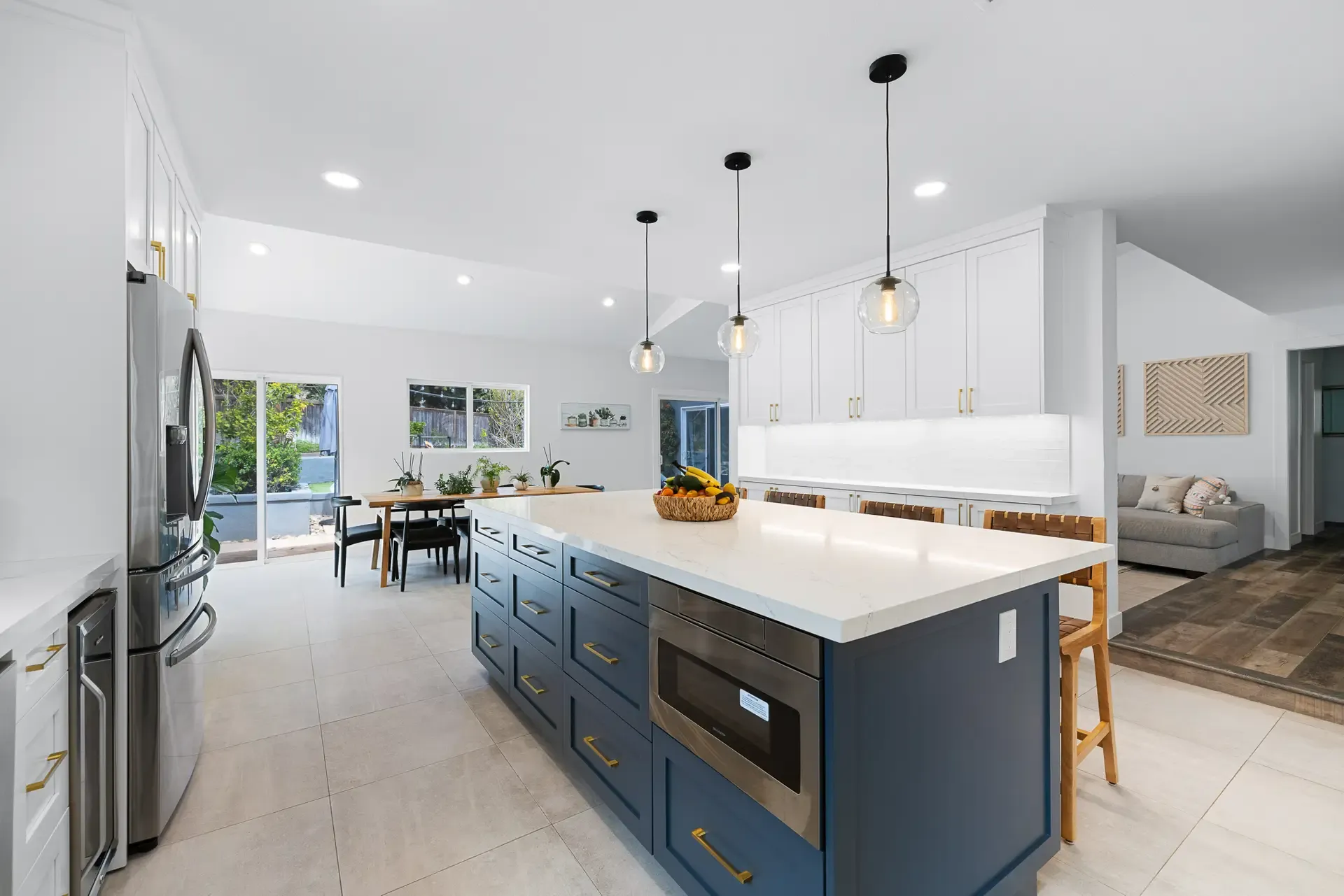 Two-tone kitchen with navy island, pendant lighting and built-in microwave drawer
