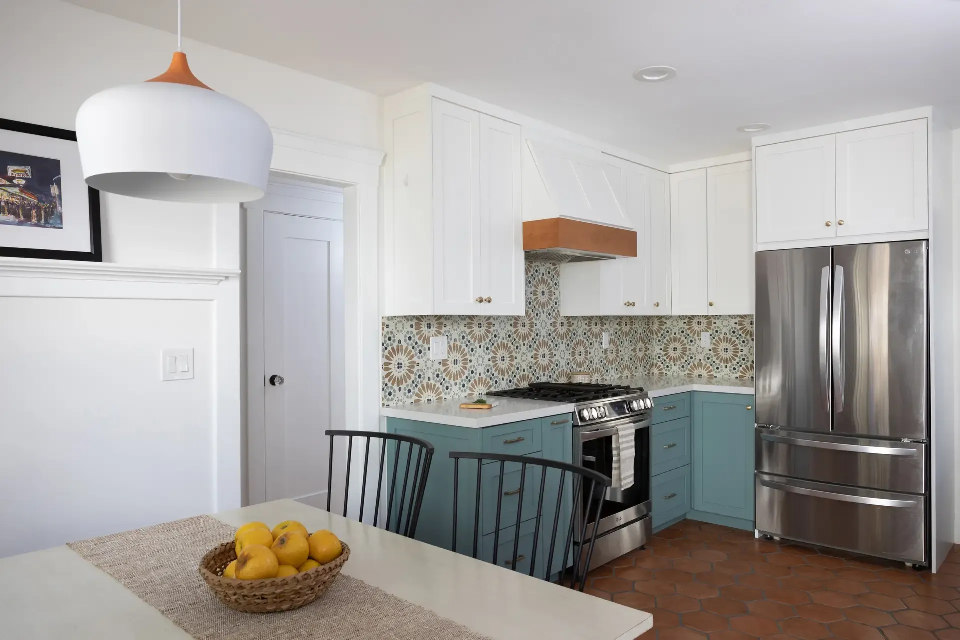 Two-tone kitchen with white uppers, teal lowers, stainless fridge, and patterned tile backsplash