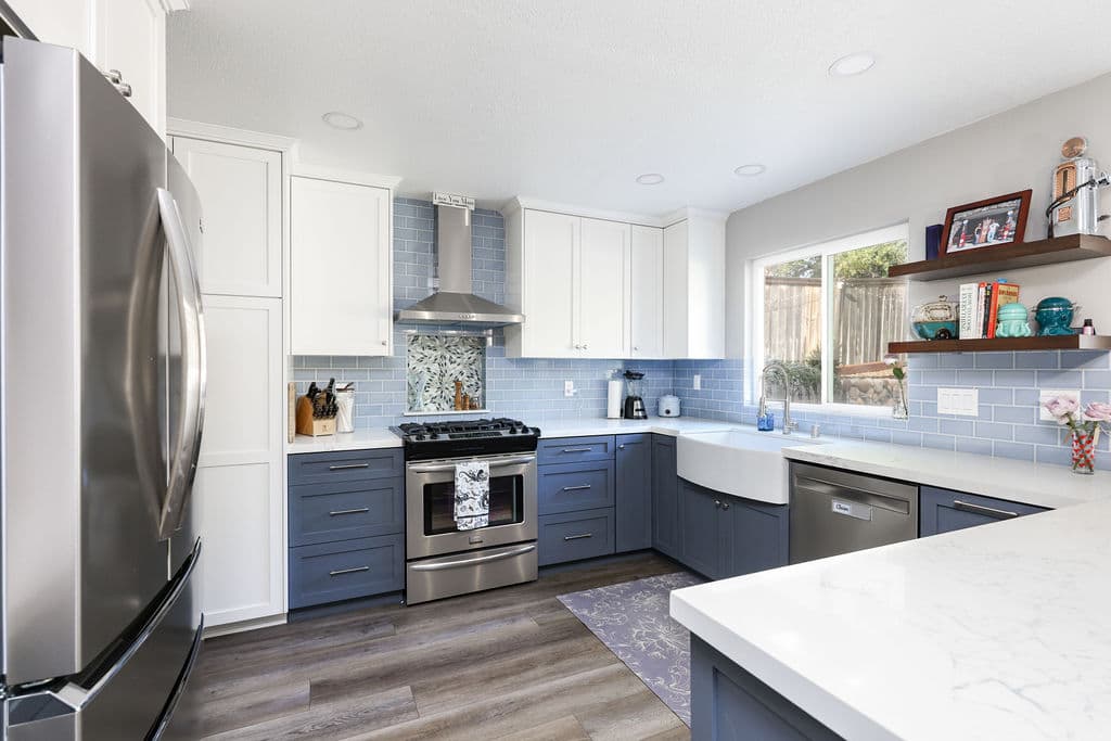 U-shaped kitchen with stainless appliances, white quartz counters and apron-front sink