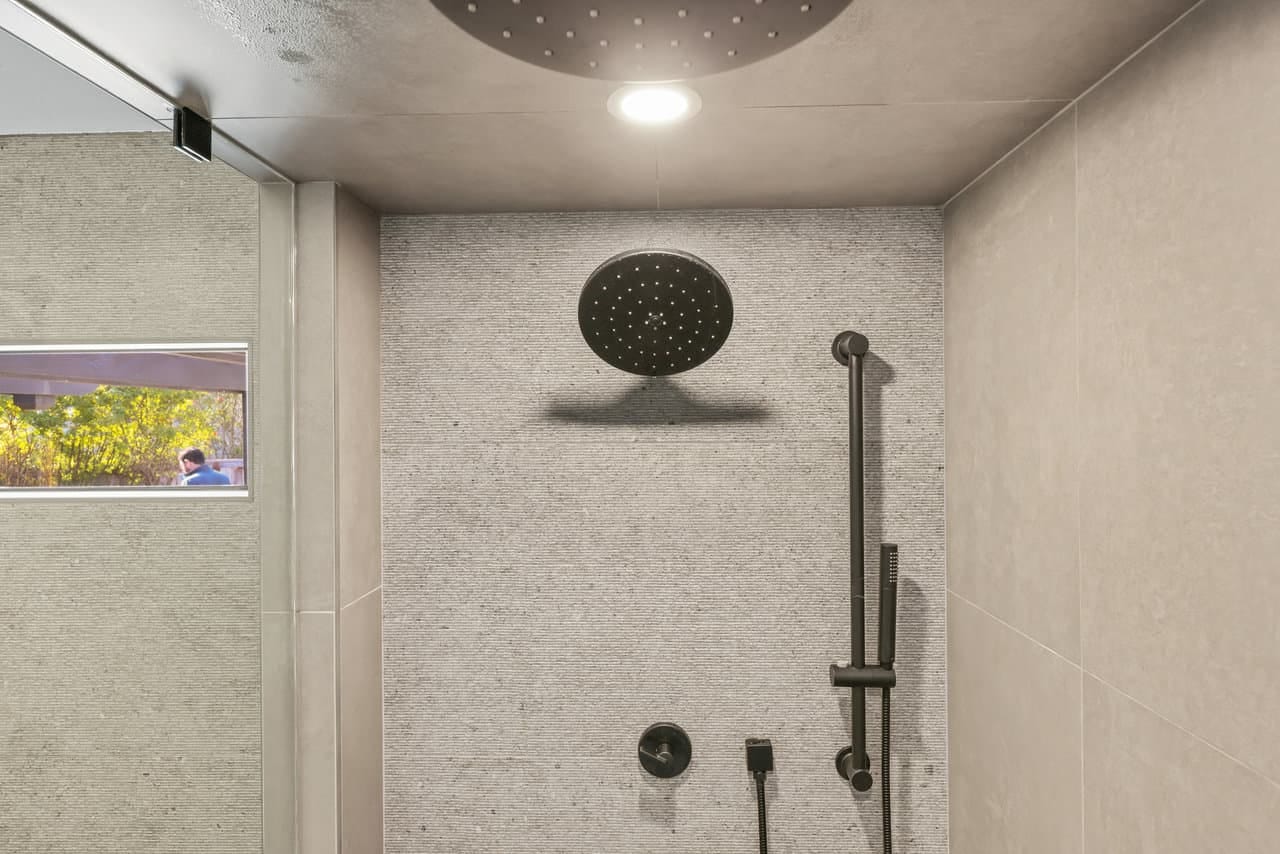Walk-in shower with black rainfall showerhead and stacked stone accent wall