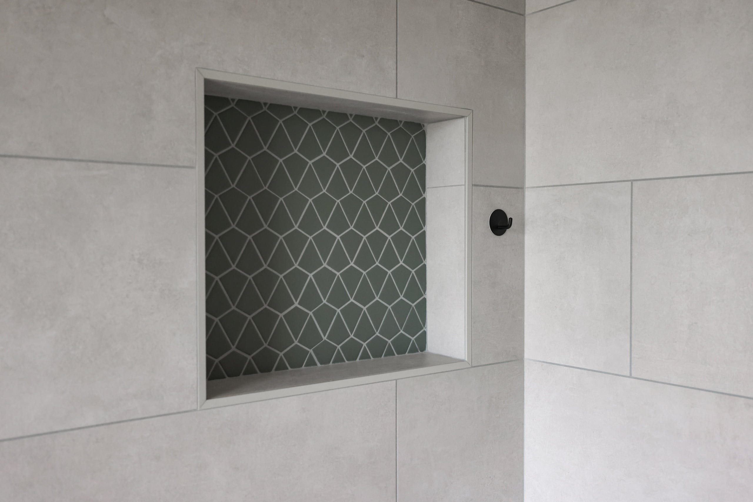 Walk-in shower with large gray tile and green arabesque-tile accent niche