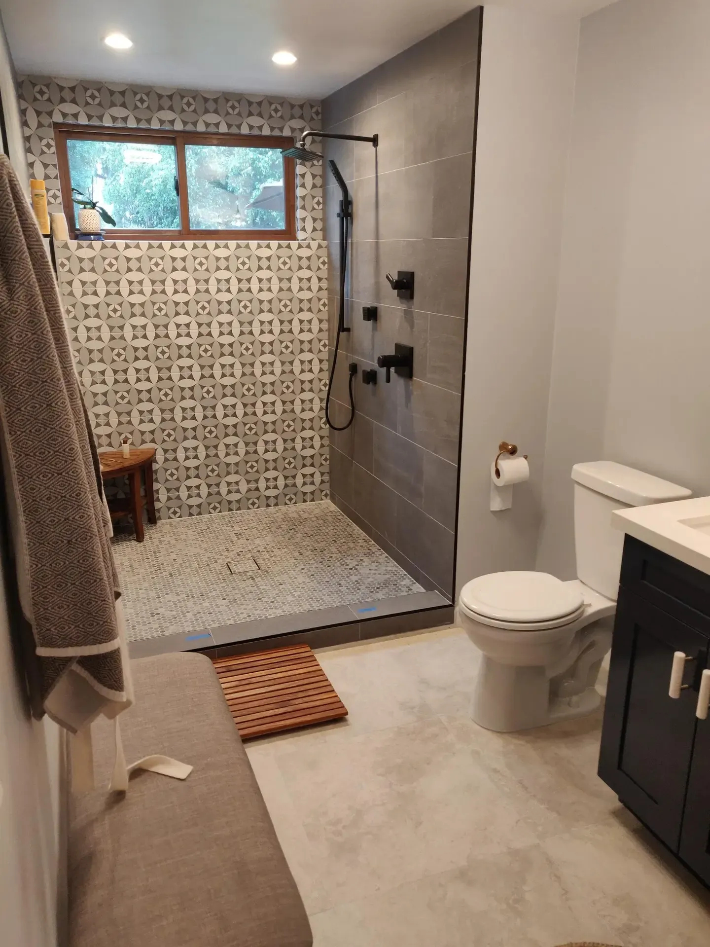 Walk-in shower with patterned tile accent wall and pebble floor, modern bathroom
