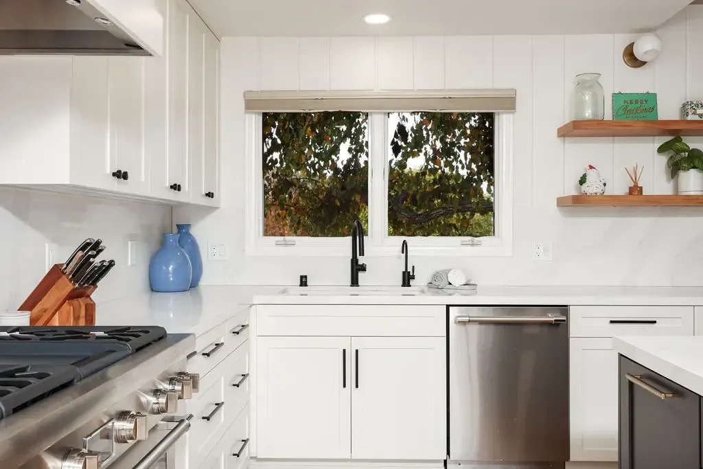 White kitchen with double windows over sink, subway tile and open wood shelves