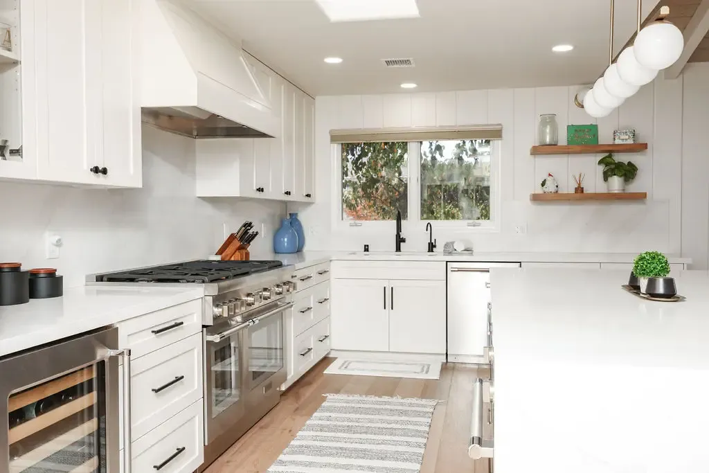 White shaker kitchen with stainless range, quartz counters and open wood shelving