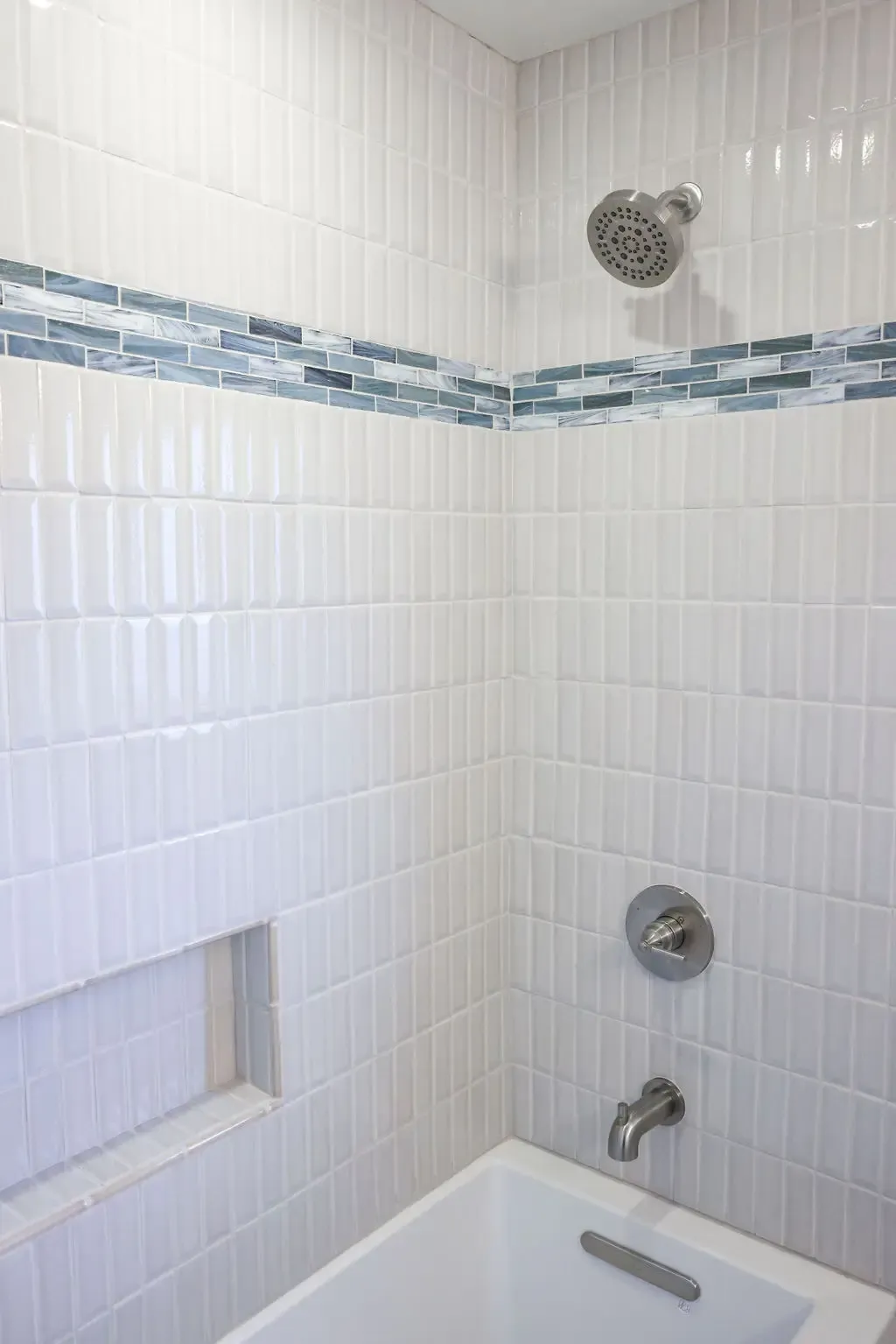 White subway-tiled tub surround with blue glass mosaic accent stripe