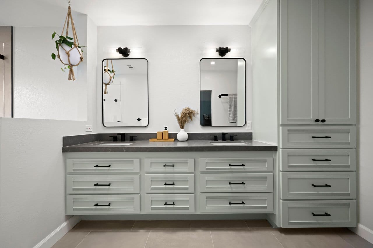 Floating double-sink vanity in soft green with gray stone top and twin black mirrors