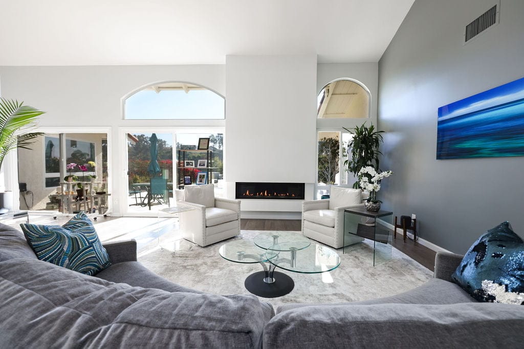 Bright living room with vaulted ceiling, linear gas fireplace and arched window walls